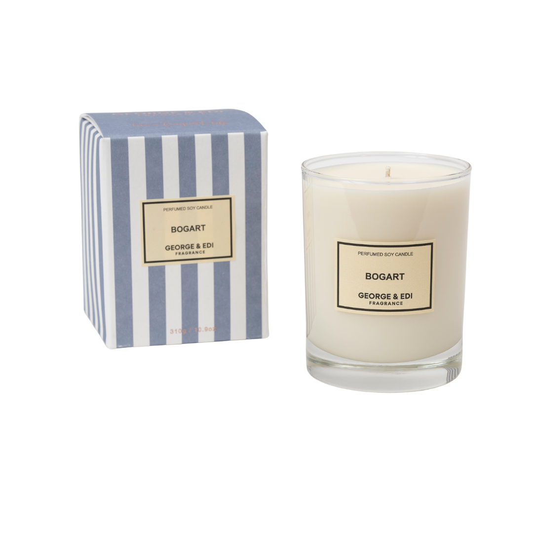 A large GEORGE & EDI soy wax candle on a glass in a striped gift box